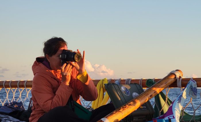 Woman on a boat holding a camera to take a picture.