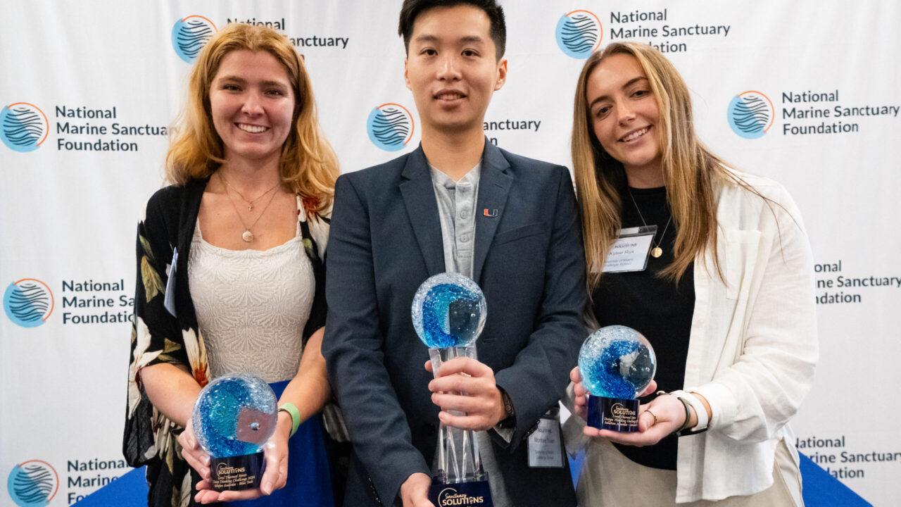 Three students holding trophies