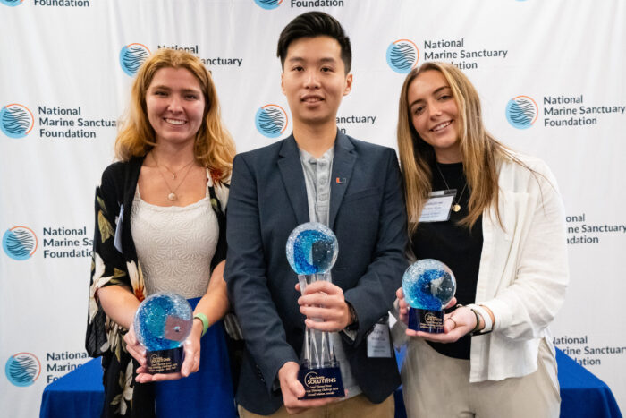 Three students holding trophies